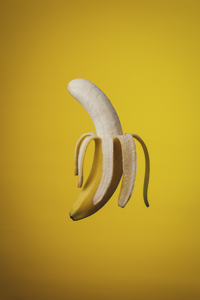 Kreatywna fotografia produktowa - obrany banan na żółtym tle